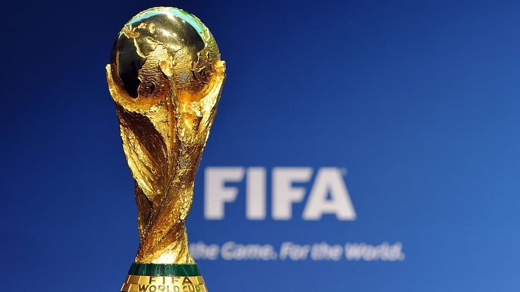 Trofeo de la Copa Mundial de la FIFA frente al logo del organismo sobre fondo azul