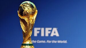 Trofeo de la Copa Mundial de la FIFA frente al logo del organismo sobre fondo azul