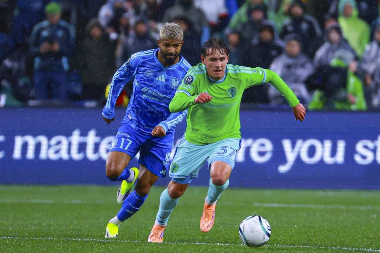Un jugador de Tigres UANL (#17) y un jugador de Seattle Sounders (#37) disputan la pelota bajo la lluvia en Lumen Field durante la vuelta de cuartos de la Concacaf Champions Cup 2026.