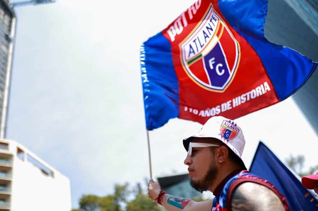 Hincha del Atlante sostiene bandera azulgrana con el escudo del club y la leyenda 110 años de historia