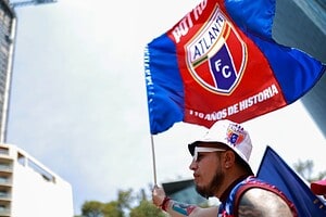 Hincha del Atlante sostiene bandera azulgrana con el escudo del club y la leyenda 110 años de historia
