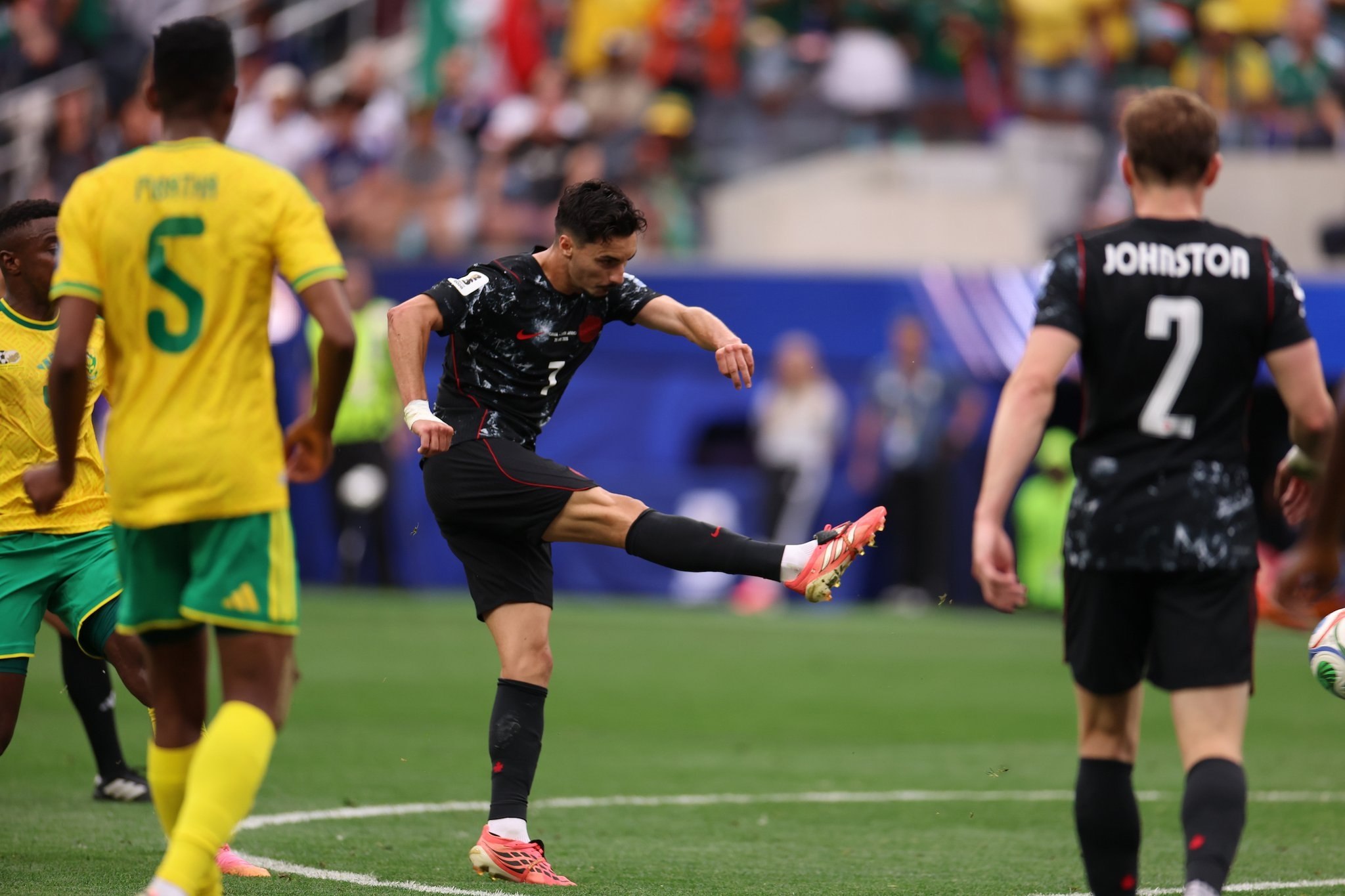 Stephen Eustáquio remata de derecha para marcar el gol de Canadá ante Sudáfrica, con el defensor Johnston de fondo