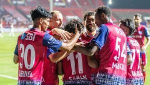 Jugadores de Jamshedpur FC se abrazan para festejar un gol con la camiseta roja y azul con el sponsor Tata Steel