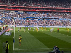 Vista del Groupama Stadium de Lyon durante un partido, con el equipo local ejecutando un córner ante una tribuna llena