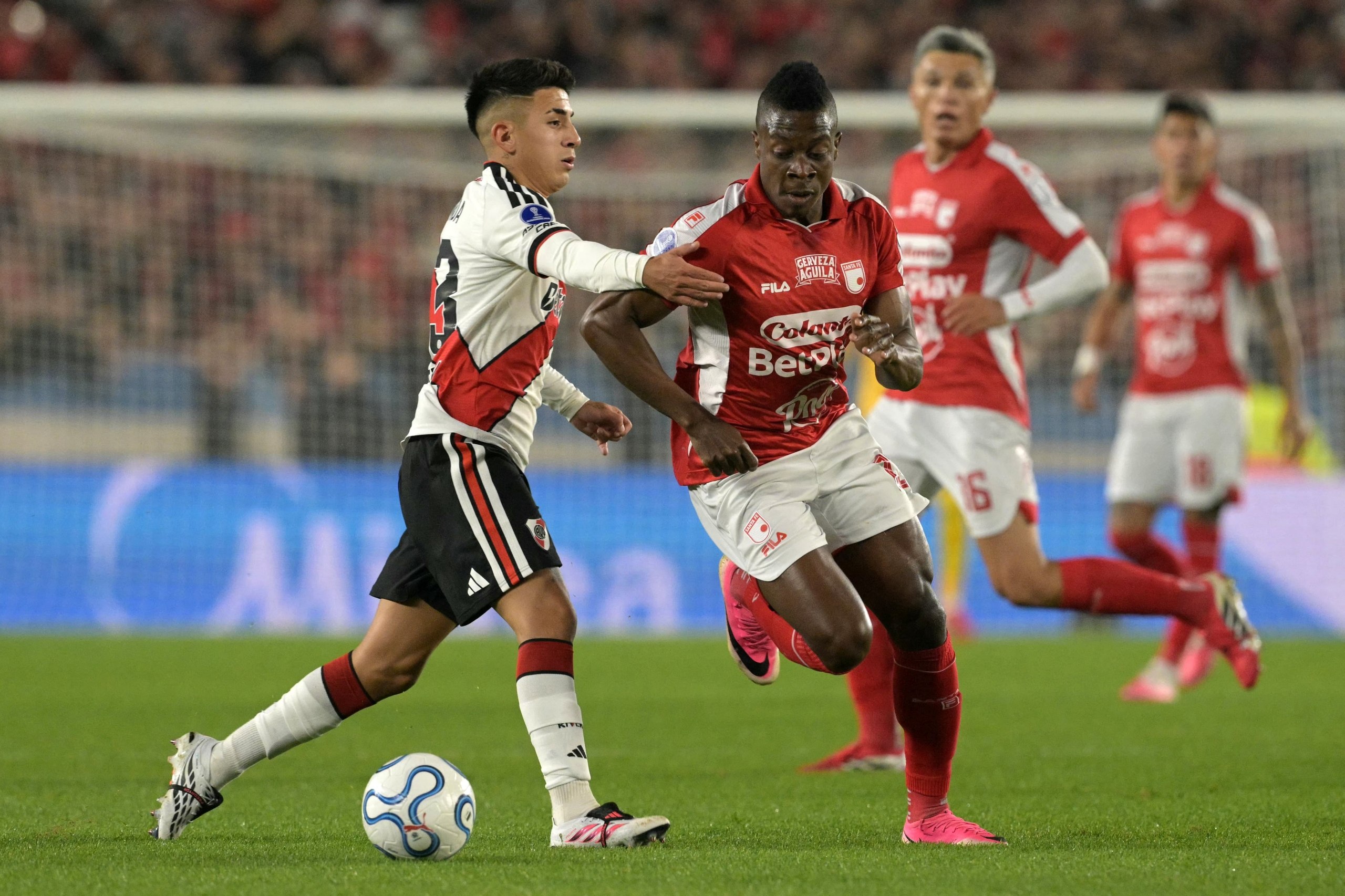 Un jugador de River Plate conduce la pelota presionado por un futbolista de Independiente Santa Fe en el Estadio Monumental