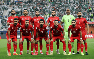 Jugadores de la selección de Bahréin posan con la camiseta roja antes de un partido en un estadio lleno