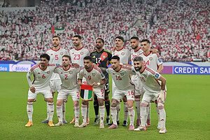 Los once titulares de la selección de Emiratos Árabes Unidos posan para la foto grupal antes de un partido, con camiseta blanca y la tribuna llena de fondo