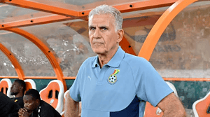 Carlos Queiroz con una camiseta de Ghana junto al banco de suplentes