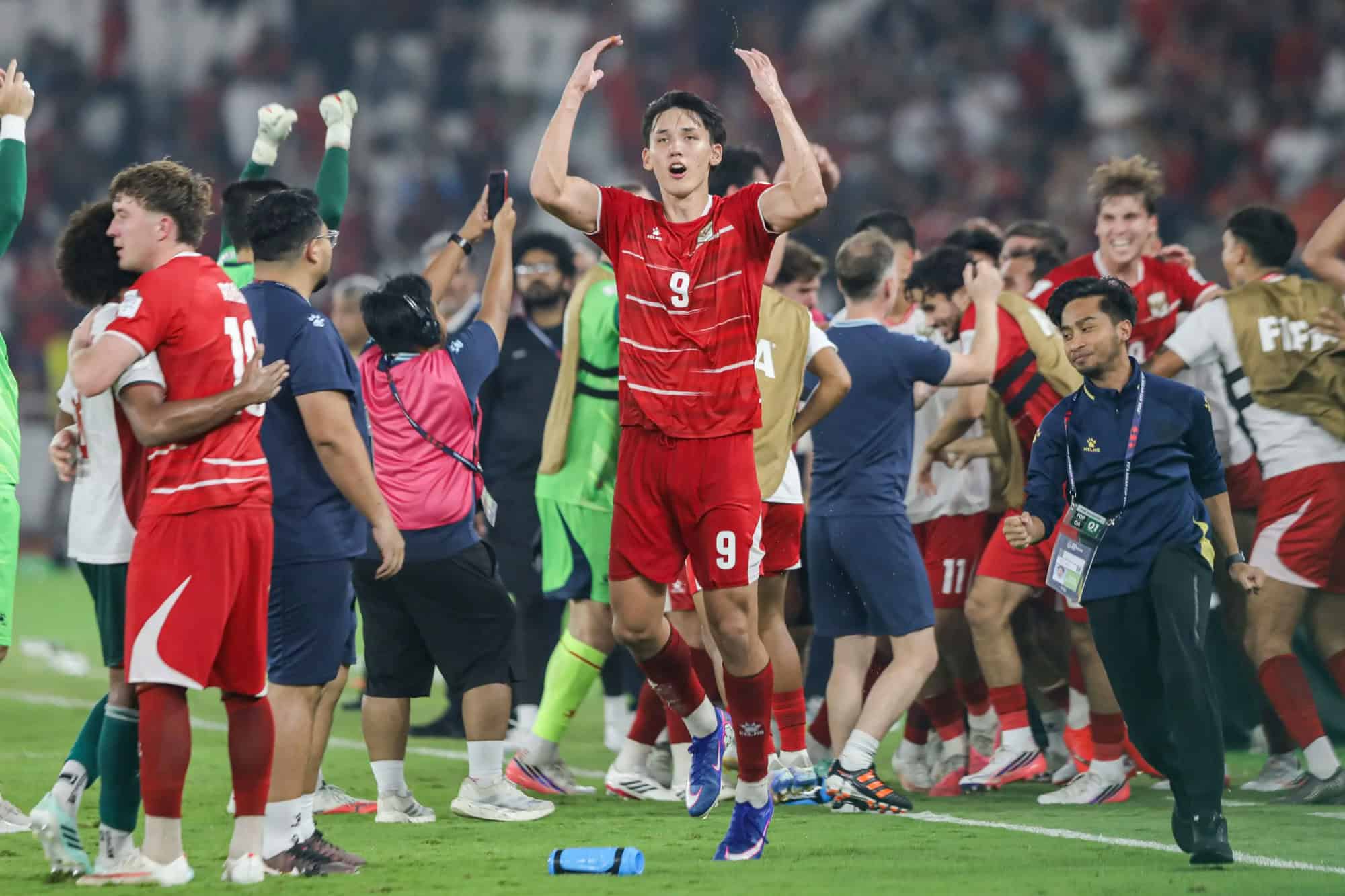 Futbolistas de la selección de Indonesia celebran en el campo de juego, con un jugador de camiseta roja número 9 en primer plano.
