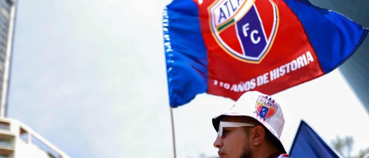 Hincha del Atlante sostiene bandera azulgrana con el escudo del club y la leyenda 110 años de historia