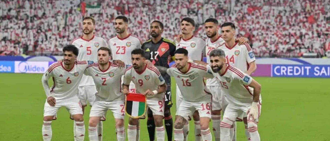 Los once titulares de la selección de Emiratos Árabes Unidos posan para la foto grupal antes de un partido, con camiseta blanca y la tribuna llena de fondo