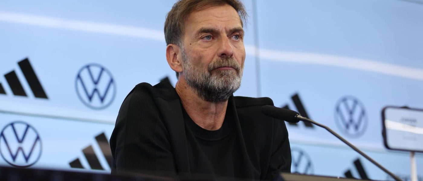 Jürgen Klopp sentado ante los micrófonos en la sala de prensa del DFB-Campus, con el fondo de patrocinadores de la selección alemana